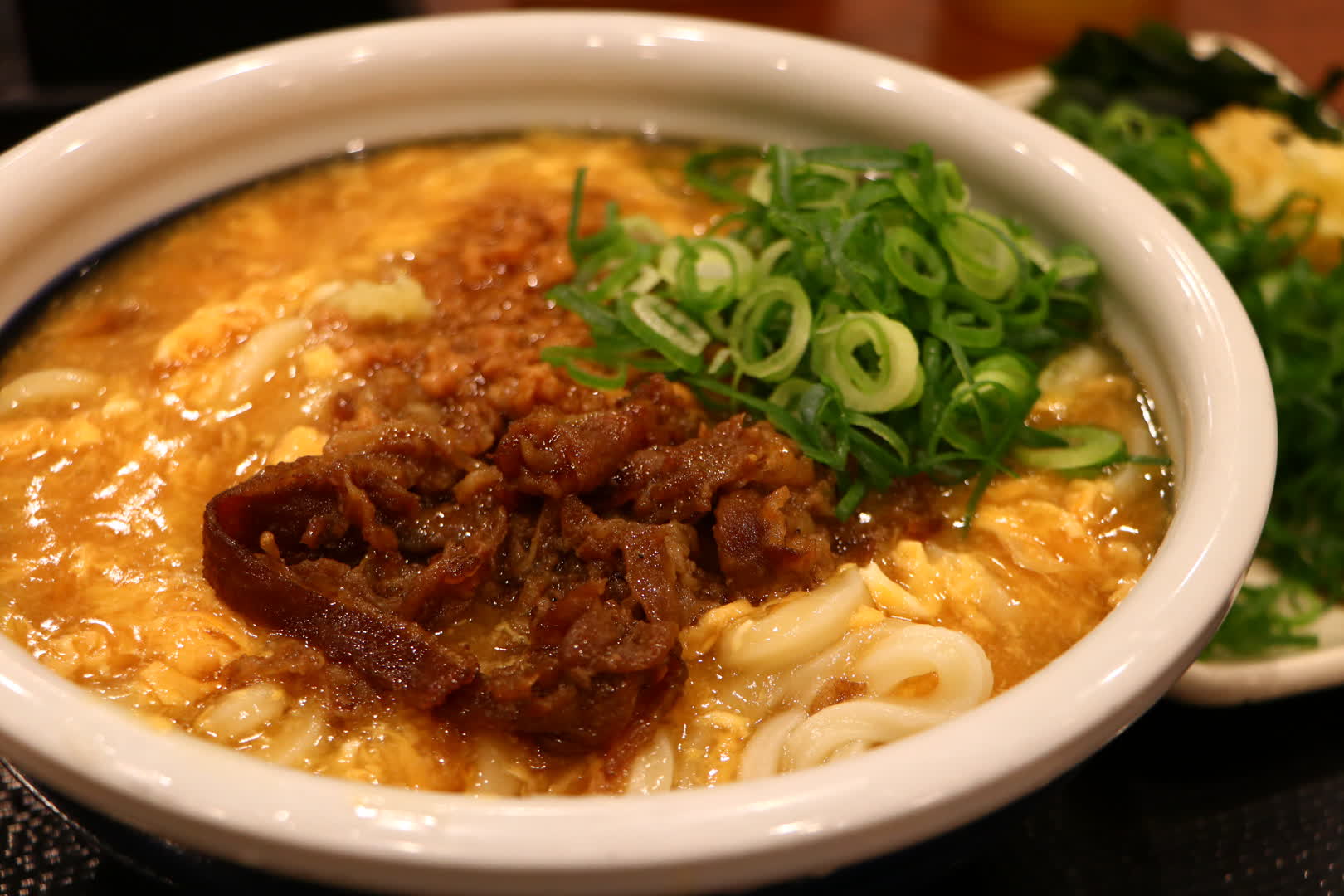 丸亀製麺の「肉がさね玉子あんかけうどん」の得サイズ。トッピングのねぎを追加してある。